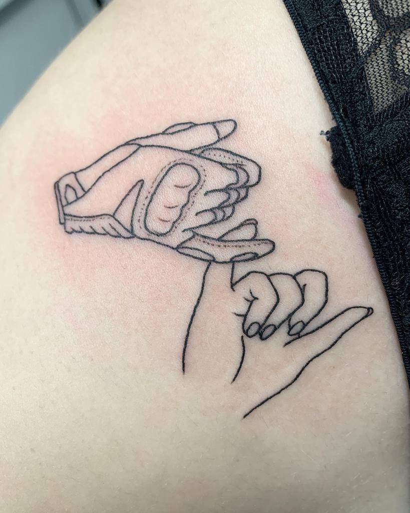 Detailed pinky promise tattoo with fine line art placed on the ribcage, next to a lace fabric edge