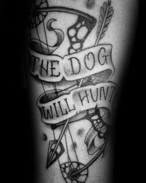 Black and grey tattoo of a compound bow with an arrow, wrapped in a banner that reads "The Dog Will Hunt" in bold lettering.