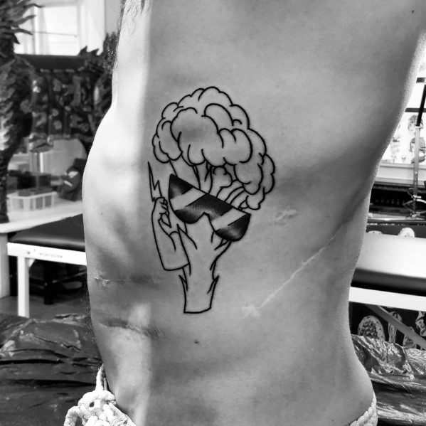 Black ink broccoli tattoo on the ribs, featuring bold outlines and sunglasses for a cool and playful design with a minimalist touch.
