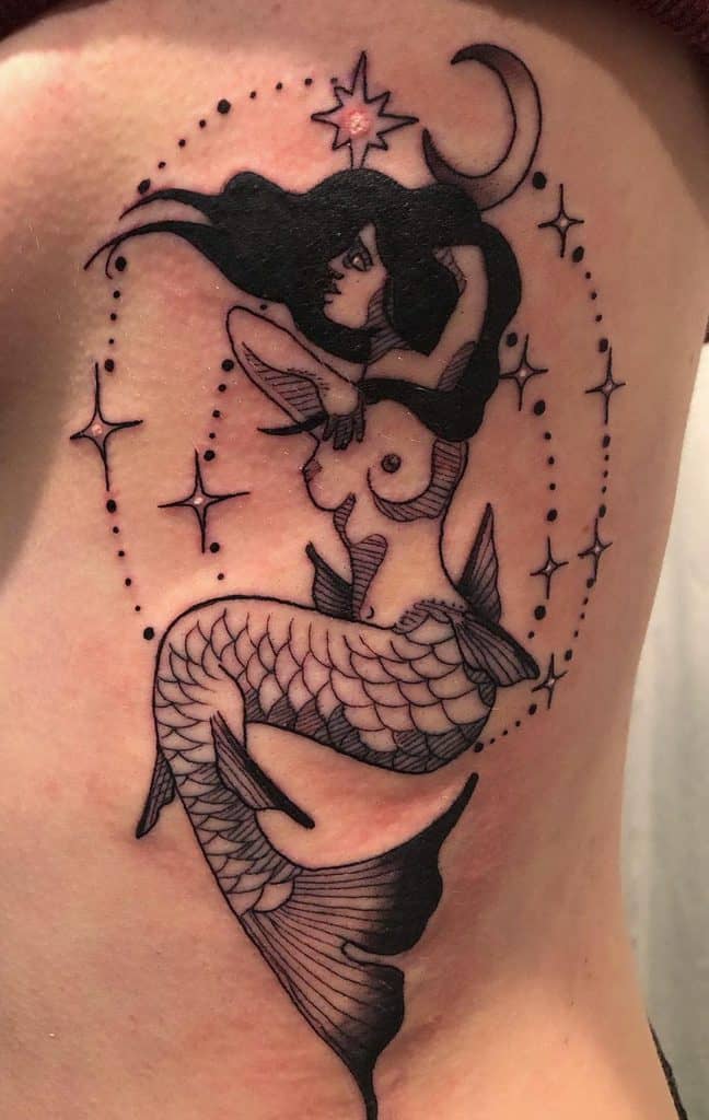 Black ink tattoo of a siren with flowing hair, surrounded by stars and a crescent moon