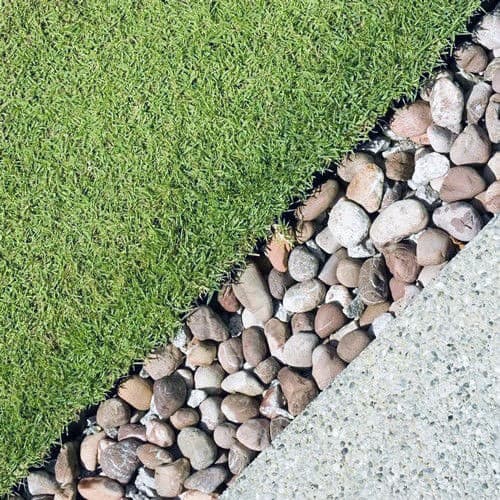 A clean boundary between lush green grass and a river rock border, providing a natural and well-defined edge