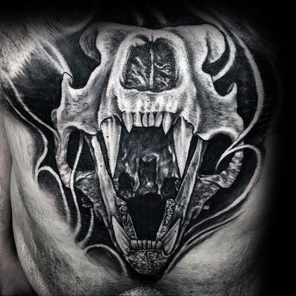 Tattoo of a roaring bear skull with sharp teeth on a person's torso