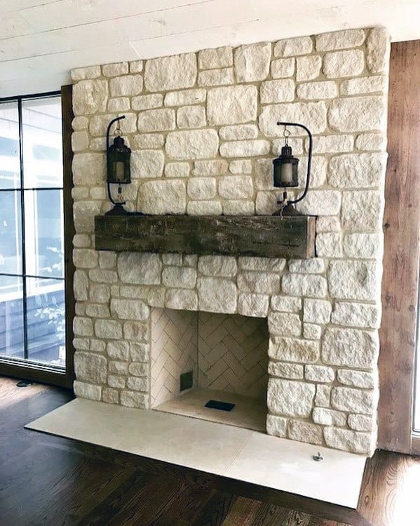 Rustic fireplace with a chunky wooden mantel, lanterns, and cream stonework.