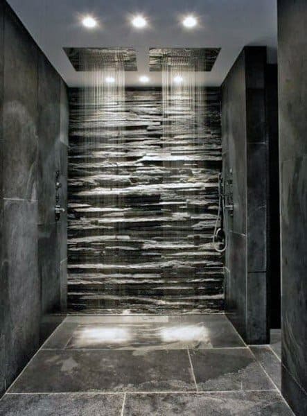 Modern shower boasting dual rainfall showerheads, elegant slate tiles, and subtle ambient lighting