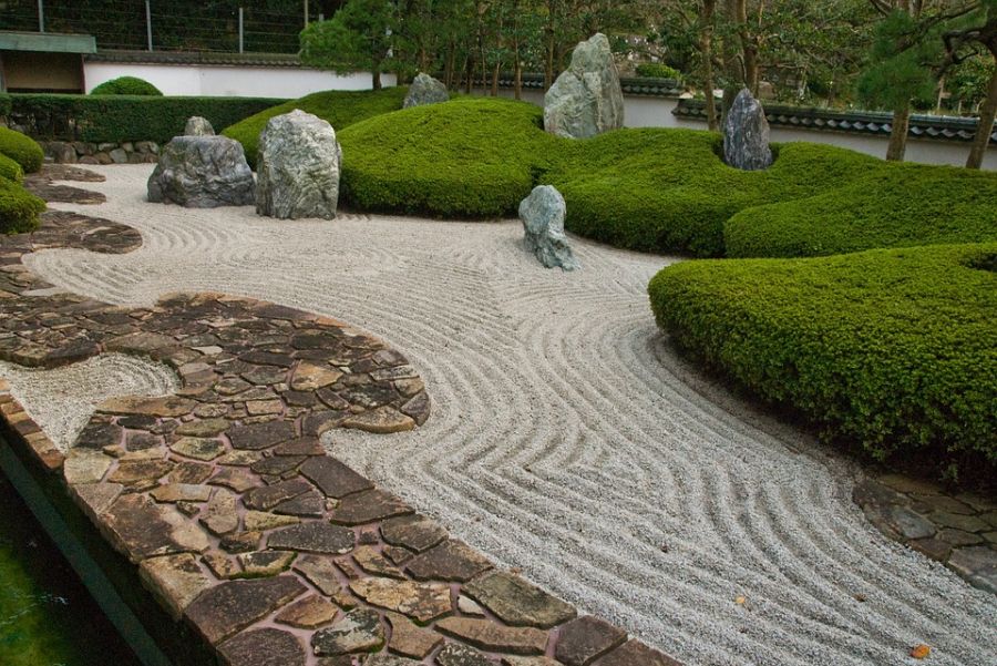 sand zen garden green shrubs paved path