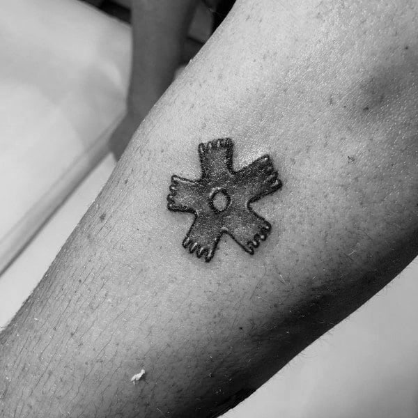Small black and grey tattoo of a spur rowel, featuring simple shading and fine details, symbolizing Western and rodeo culture.