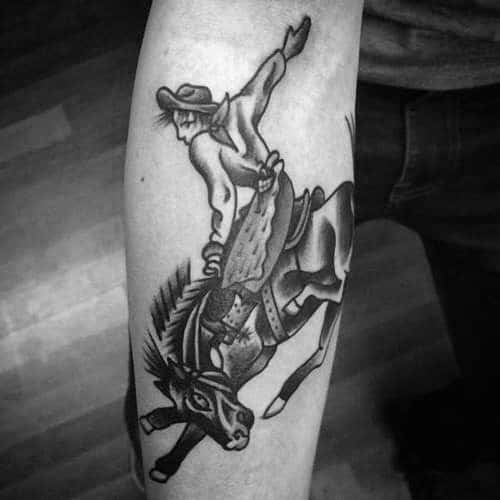 Black and grey traditional-style tattoo of a cowboy riding a bucking horse, featuring bold outlines, strong shading, and dynamic Western motion.