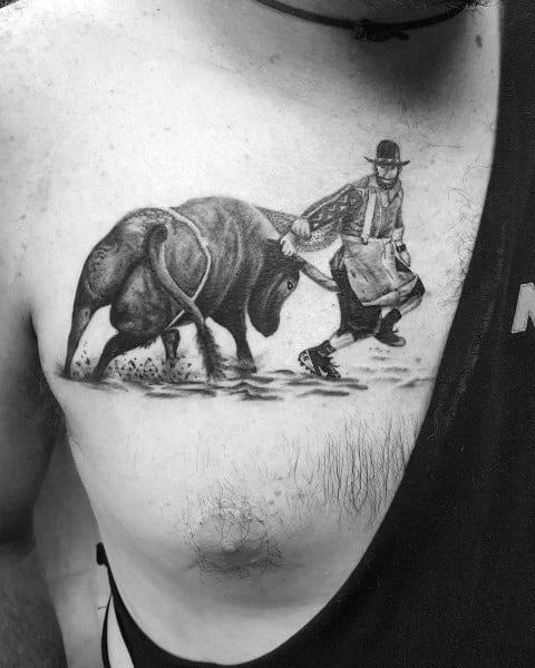 Realistic black and grey tattoo of a rodeo bullfighter dodging a charging bull, featuring fine details, shading, and dynamic movement.