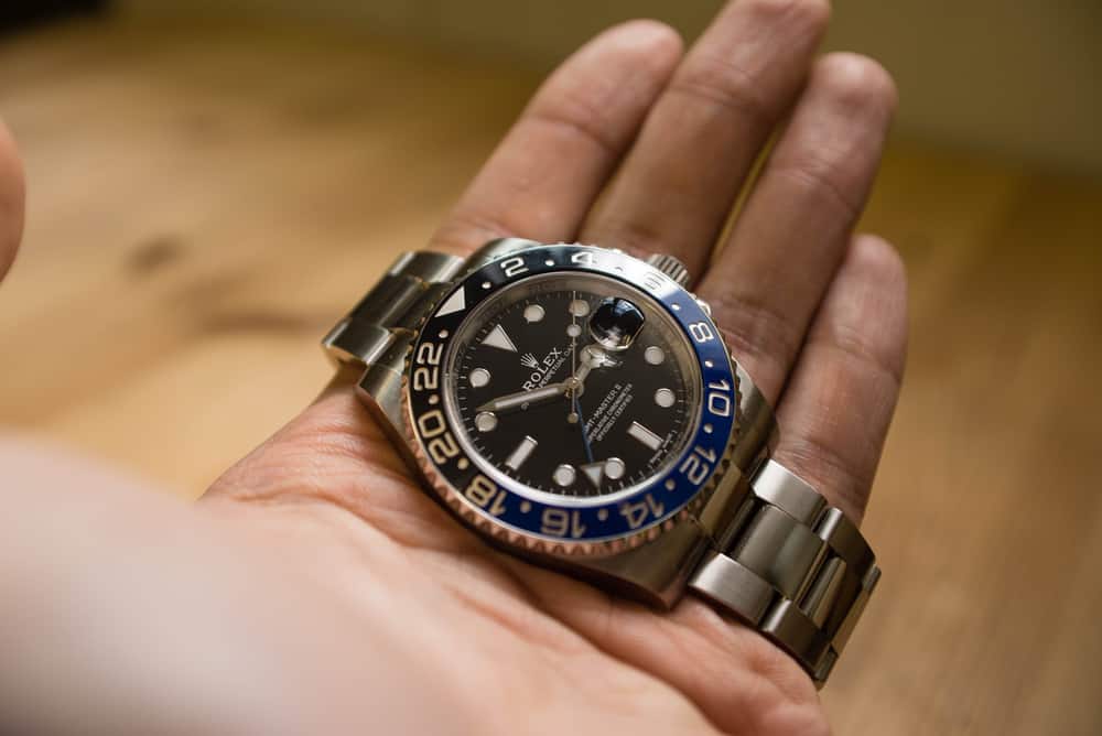 rolex gmt master II on a hand in front of a wood grain background