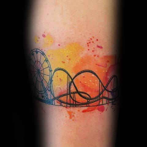 Roller coaster and Ferris wheel tattoo with black outline over a watercolor-style orange and red sunset splash background.