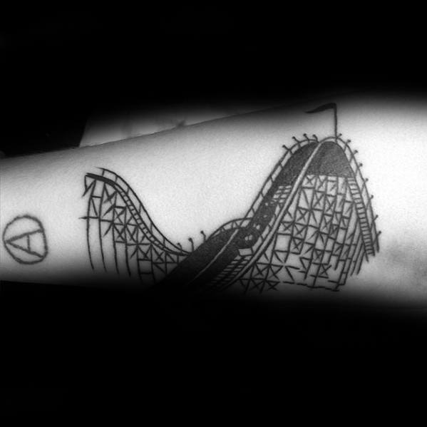 Black line tattoo of a classic wooden roller coaster with detailed support beams and a small flag at the top of the tallest hill.