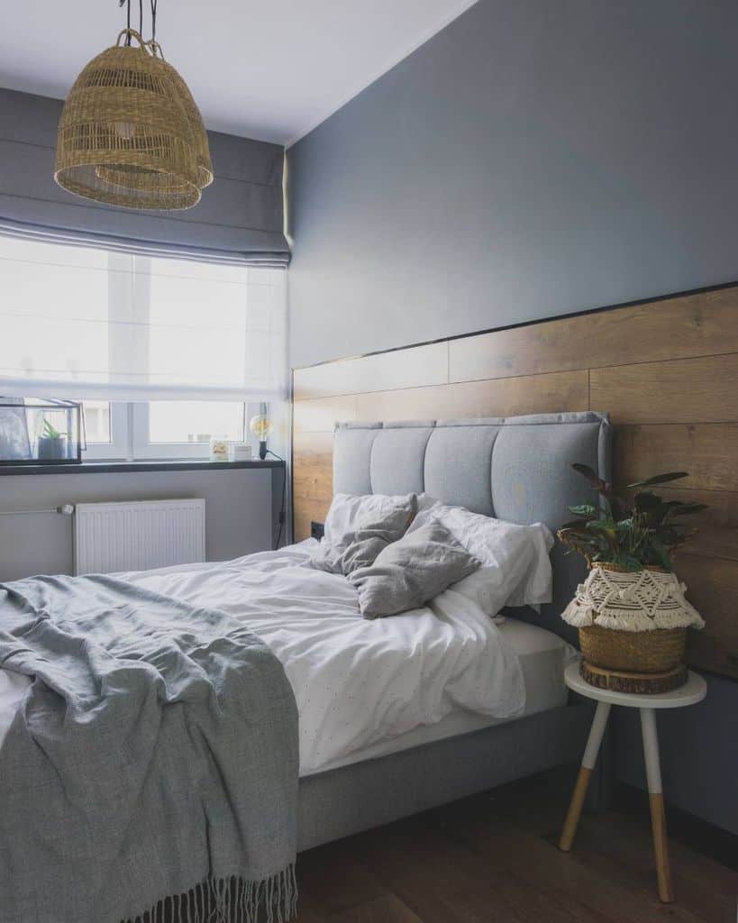 Modern bedroom with wood accent wall, gray bedding, and woven pendant light.