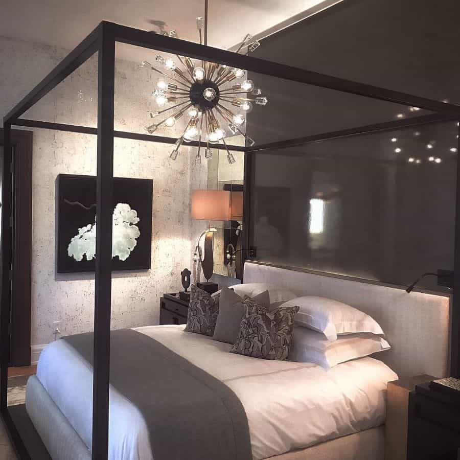 Modern bedroom with a four-poster bed, layered bedding, abstract wall art, and a unique chandelier