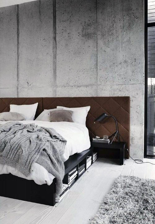 Industrial bedroom with concrete wall, cozy bed, nightstand, and a shag rug