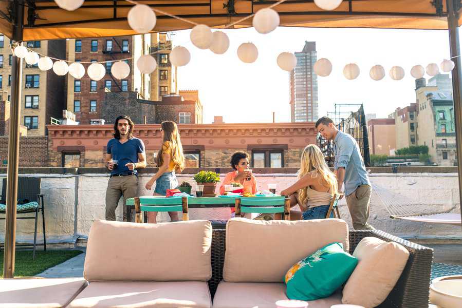 Group of people enjoying a casual gathering at a rooftop bar with city views.