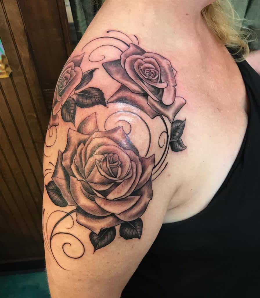 Black and gray rose tattoo with swirls graces the upper arm and shoulder