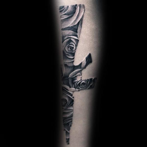 Black and grey AR-15 silhouette tattoo filled with detailed roses, blending strength and elegance, symbolizing contrast between power and beauty.