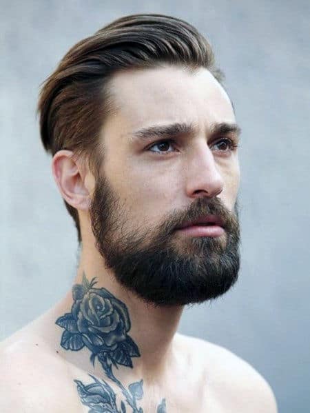 Detailed black and grey rose tattoo on the neck, paired with leaves, blending seamlessly with the wearer’s beard and style