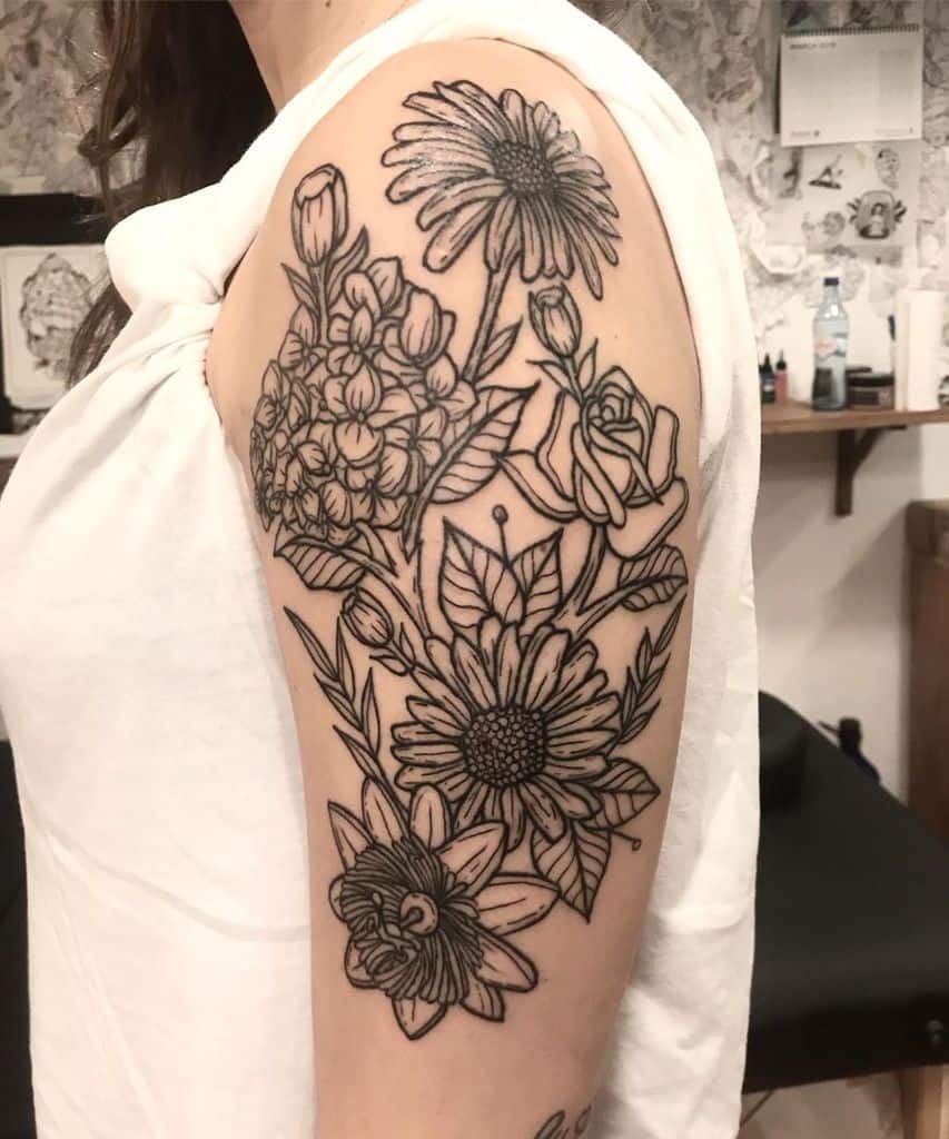Upper arm and shoulder tattoo large black line work rose orchid passion flower and daisy