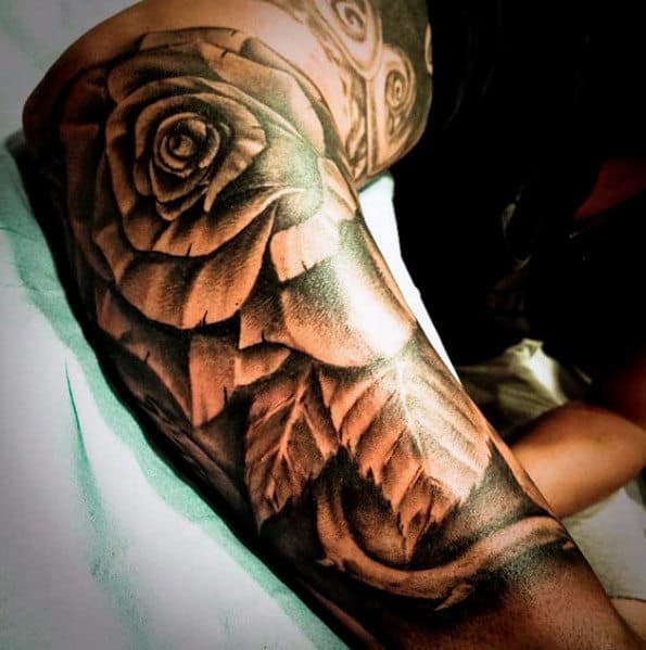 Tattoo of a realistic rose with leaves on an arm