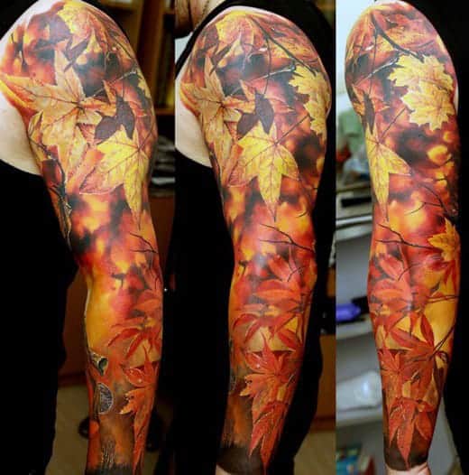 Full sleeve tattoo of autumn leaves in vibrant orange, yellow, and red hues