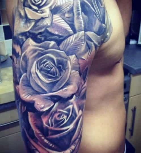 Tattoo of realistic roses with leaves on the upper arm and shoulder of a person