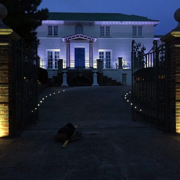 Driveway illuminated by round LED lights, guiding the path toward the elegant home and enhancing the grand entrance at twilight