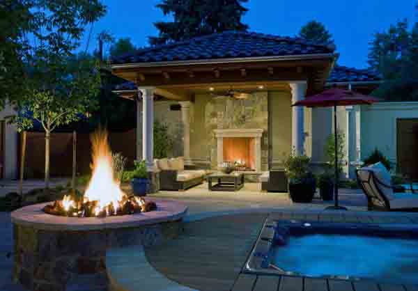 Cozy outdoor patio with a fire pit, seating area, and a hot tub at night