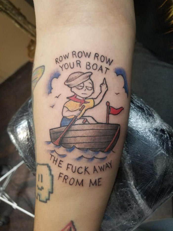 A colorful tattoo of a person rowing a boat with the phrase 'Row row row your boat the f*** away from me,' blending humor with a traditional style.