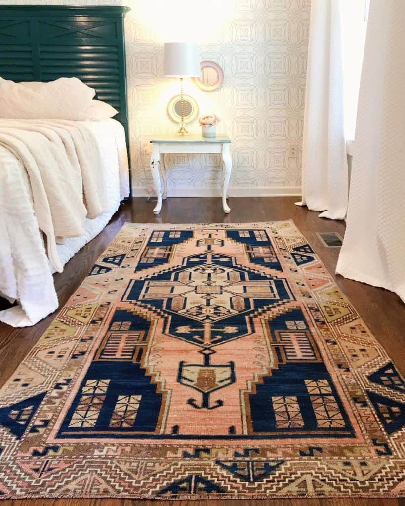 Modern bedroom with large patterned rug, green bed frame, and vintage nightstand.