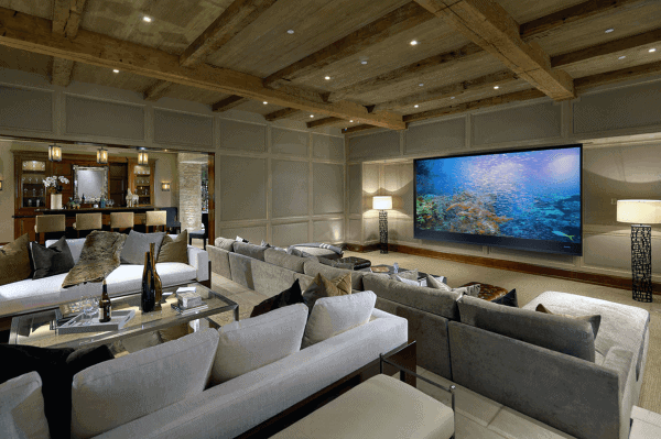 Luxurious home theater with a large screen, plush seating, wooden beams, and ambient lighting