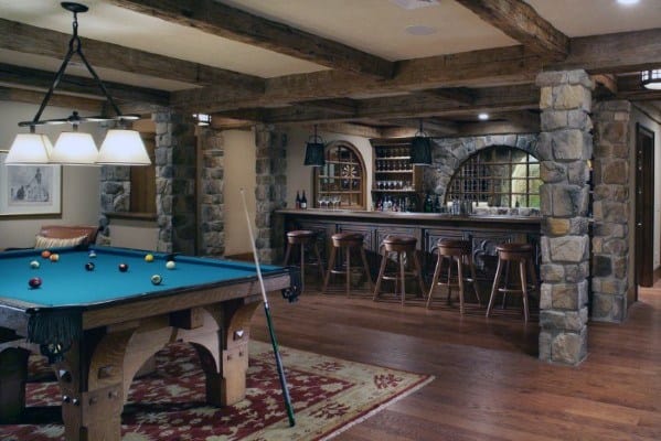 Rustic design with stone columns, wooden beams, billiard table, and a classic bar setup.