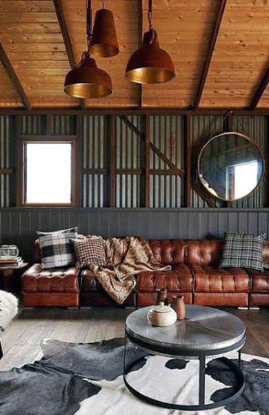 Rustic barn-style living room with leather sofa, wood-paneled ceiling, and industrial lighting.