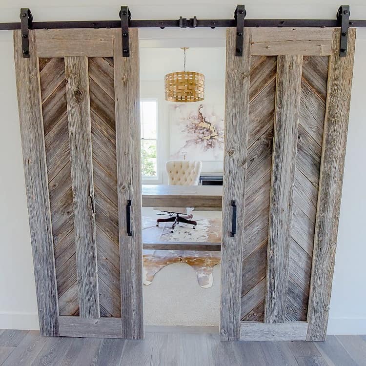 Rustic timber sliding barn doors opening to a bright, modern office space with natural decor.