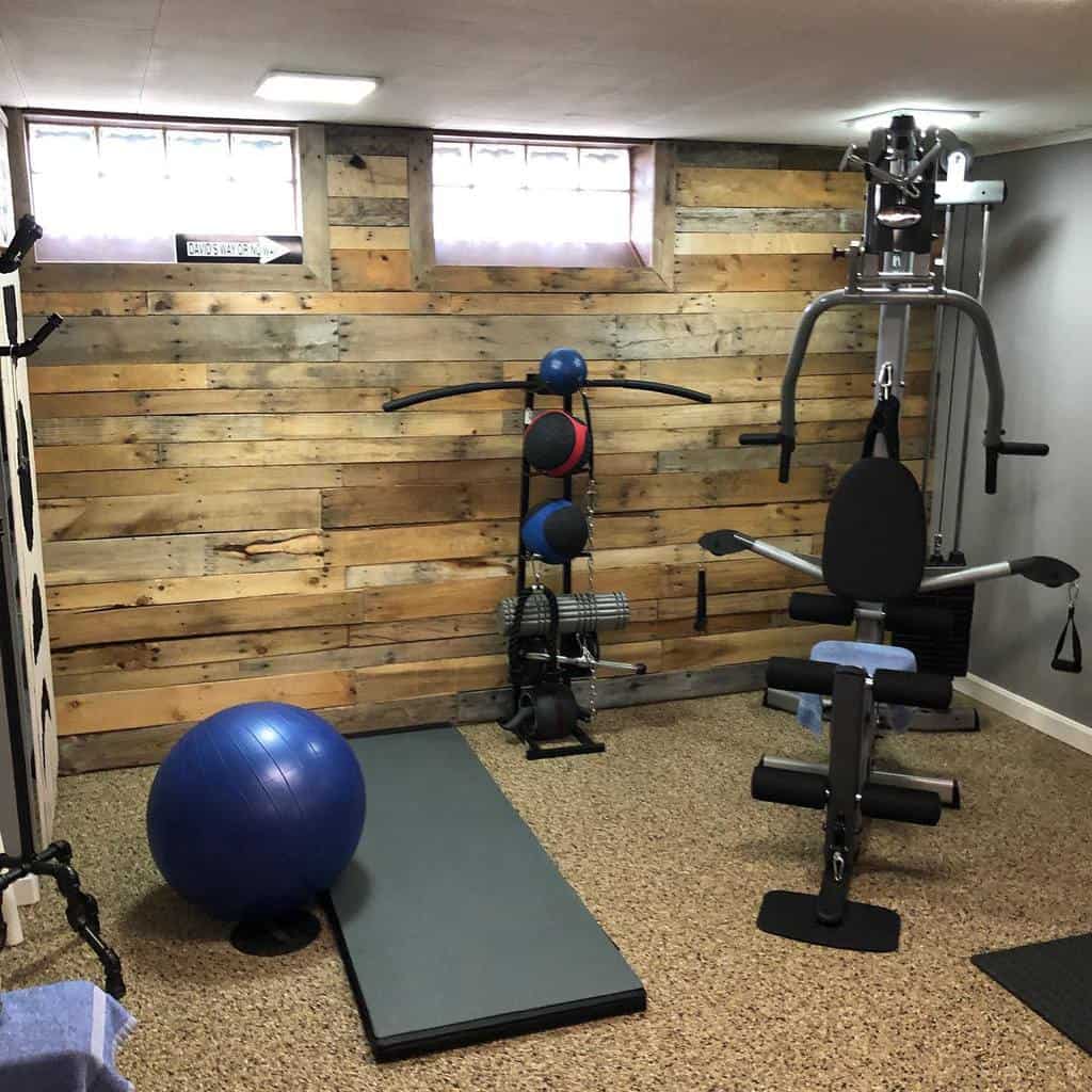 Rustic home gym with wooden accent wall, workout equipment, and yoga mat.