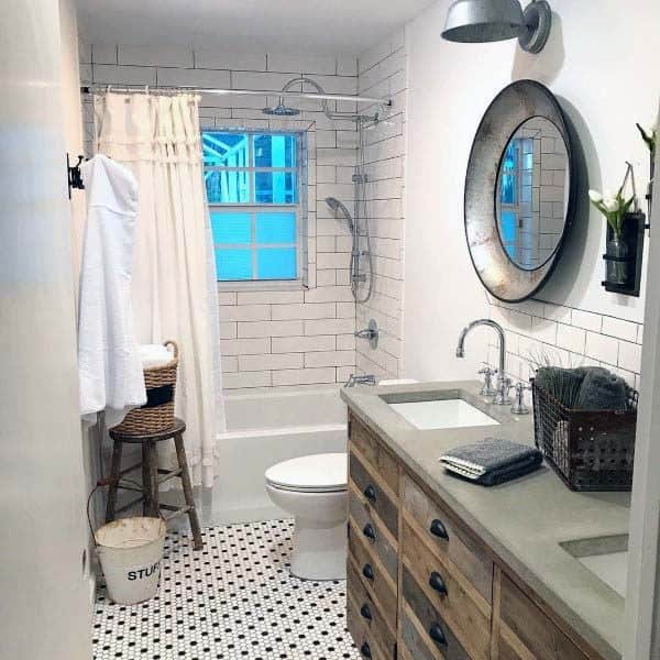 Rustic bathroom with cozy wood vanity, round mirror, and white tiles