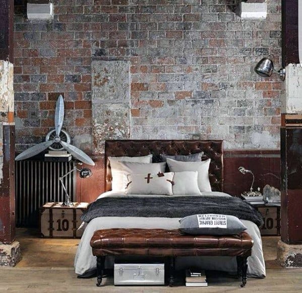 Industrial-style bedroom with exposed brick wall, tufted leather headboard, and vintage furnishings.