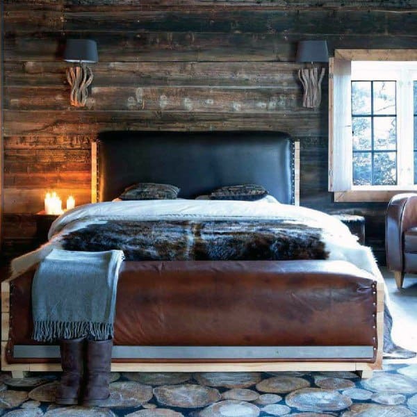 Rustic bedroom with leather bed frame log slice flooring and reclaimed wood walls.