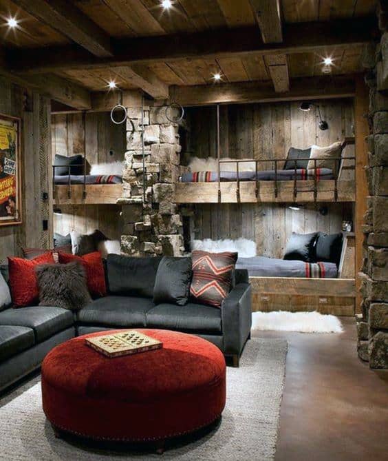 Cozy rustic retreat featuring built-in wooden bunk beds, a stone column, and a warm seating area with vibrant red accents.