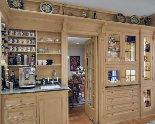 Traditional coffee bar with wooden cabinets, open shelving, sink, and espresso machine.
