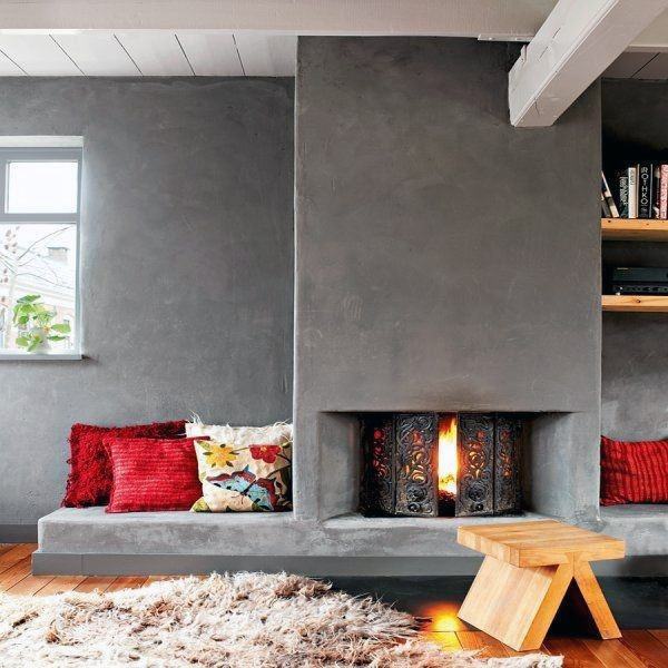 Rustic concrete fireplace with cozy built-in seating, vibrant cushions, and a textured design for warmth and charm.