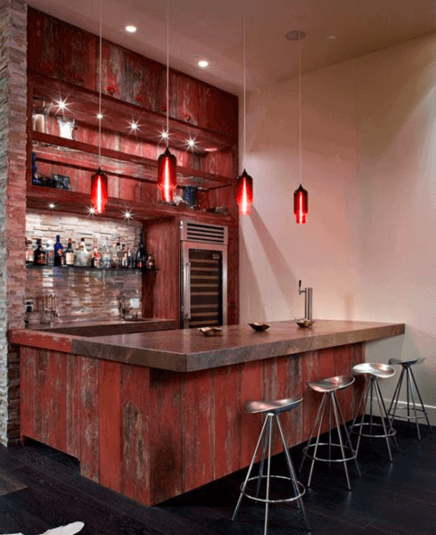 Rustic home bar with a concrete countertop, red wood accents, and modern red pendant lights.