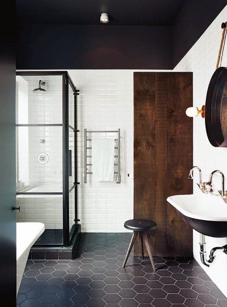 Rustic bathroom with dark painted ceiling, black hexagonal floor tiles, and glass shower.