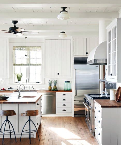 rustic country kitchen with white cabinets wood countertops and hardwood flooring 