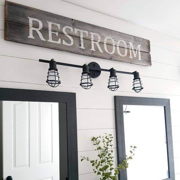 Rustic restroom sign with industrial lights, mirrors, and a white shiplap wall