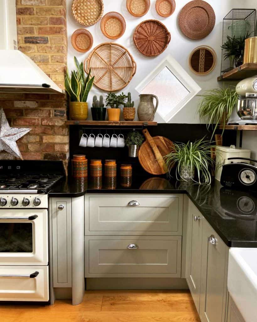 Rustic kitchen with wicker wall decor black countertops green cabinets and potted plants.