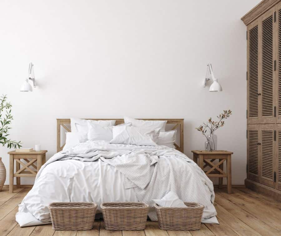 Minimalist bedroom with a wooden bed, white bedding, side tables, wall sconces, wardrobes, and wicker baskets