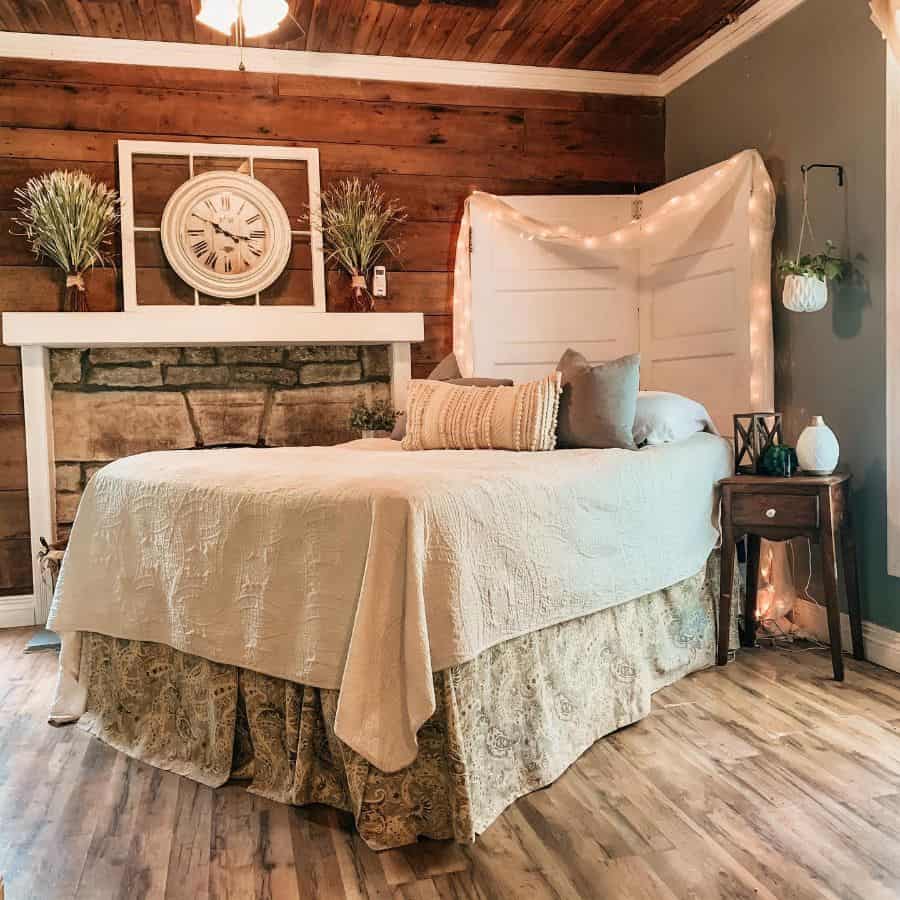 Cozy bedroom with a wooden accent wall, vintage decor, and a neatly made bed with pillows and cushions