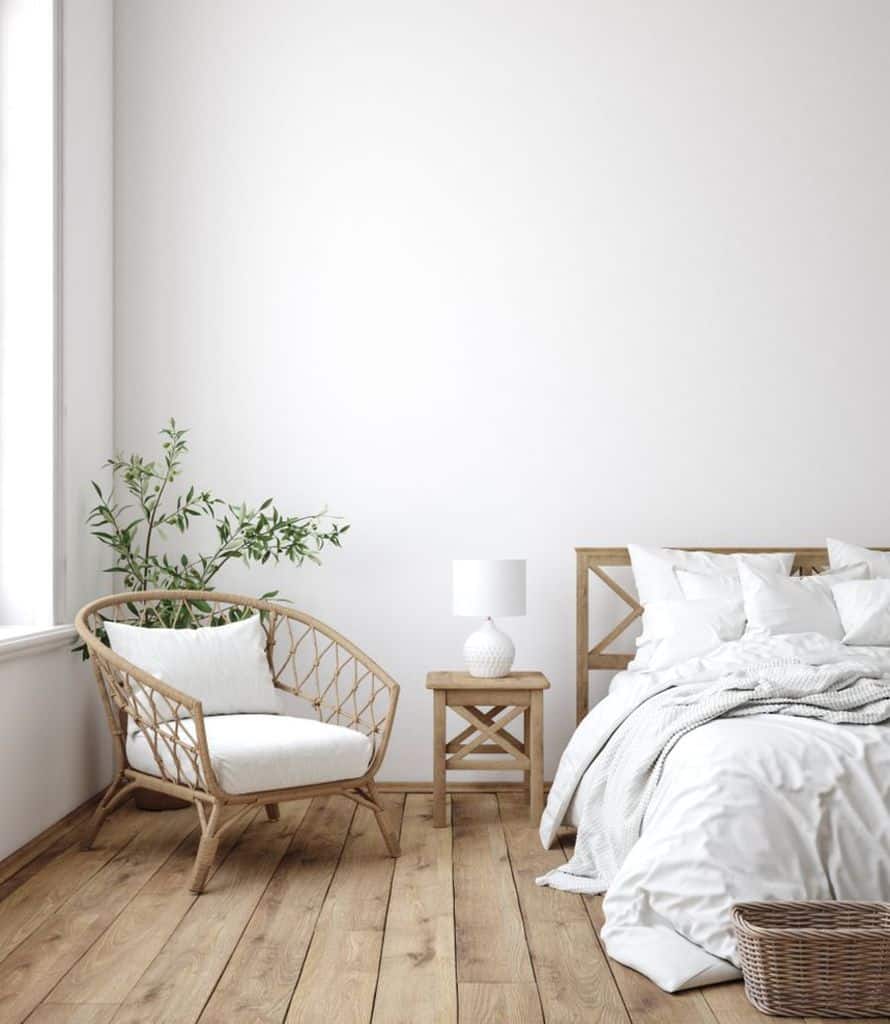 Minimalist bedroom with wooden furniture, white bedding, and potted plant for natural touch.