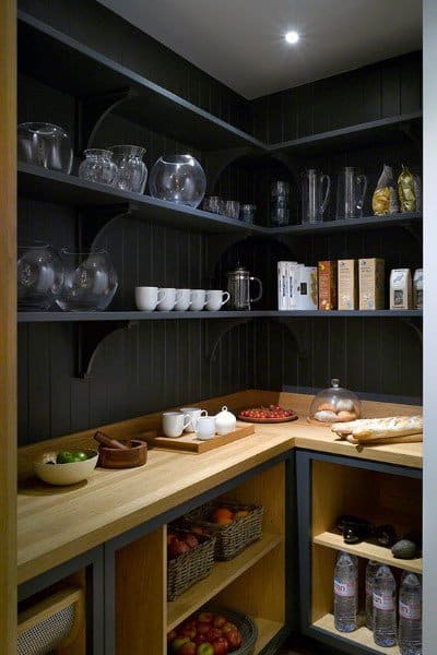 A rustic grey kitchen pantry with wooden countertops, dark shelving, and warm lighting for a cozy, organized space.